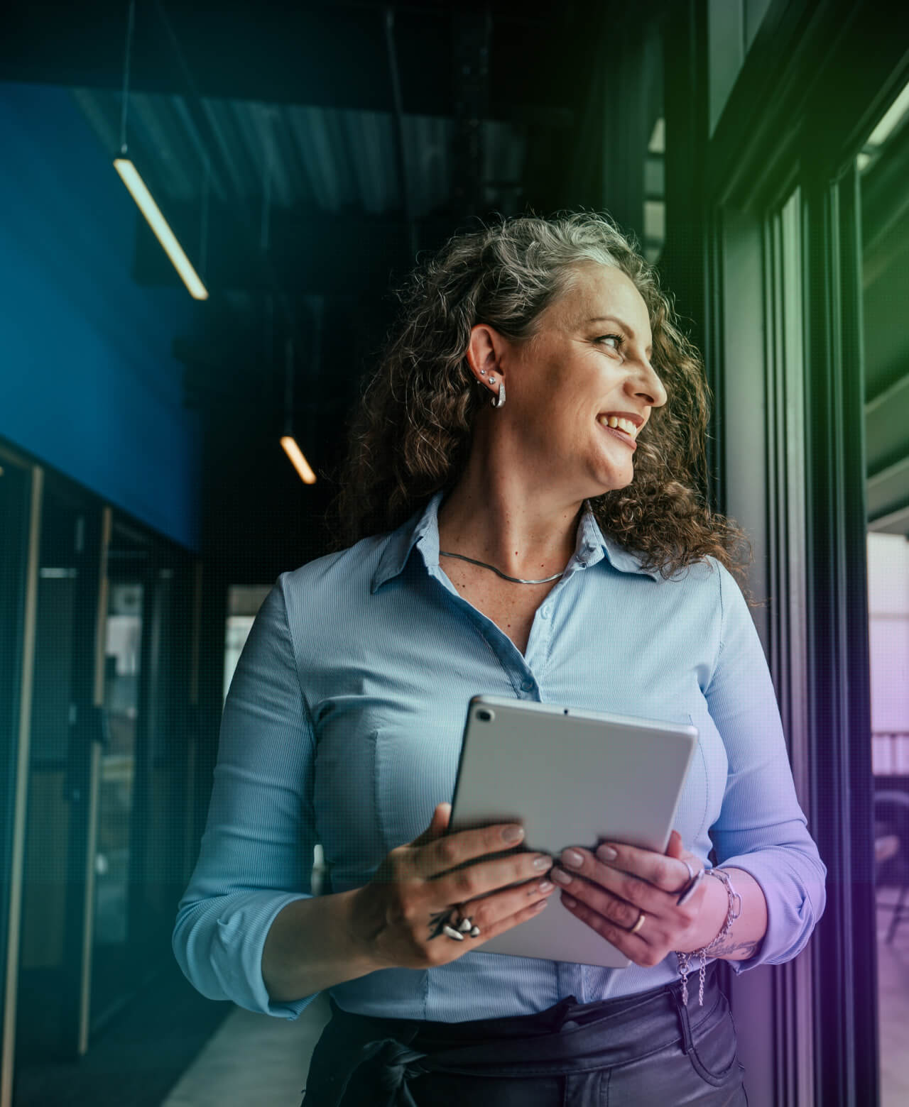 A colleague holding a tablet by a window in a modern office