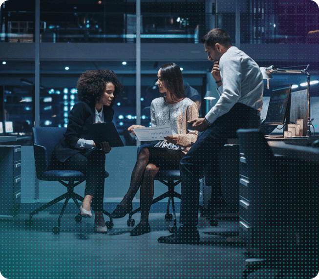 Three colleagues working over documents and a laptop in a shared office